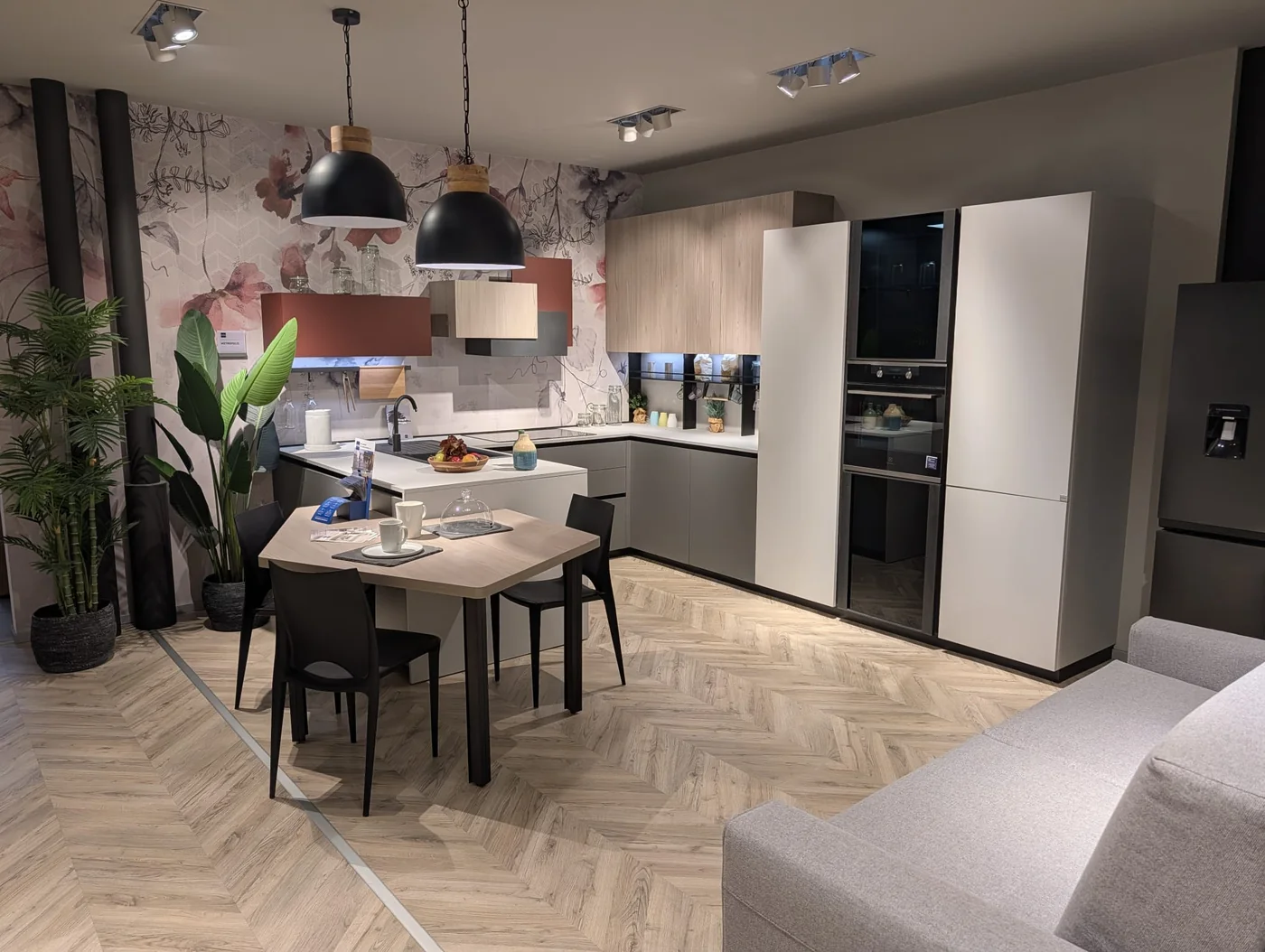 Cucina angolare con penisola Stosa Metropolis in PET grau opaco e larice sabbia, con dettagli in Fenix rosso Jaipur, nello showroom di Veduggio