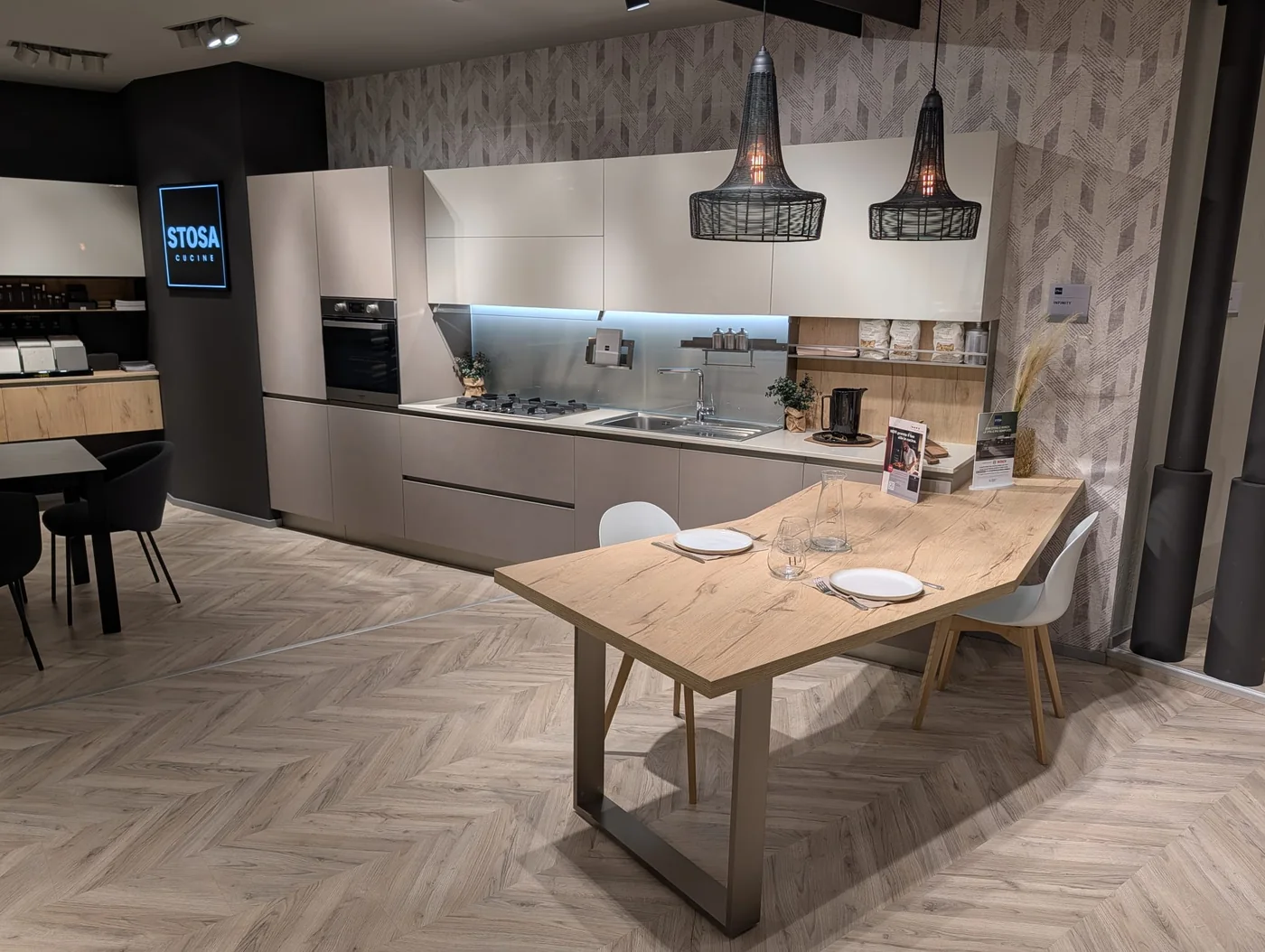 Cucina lineare Stosa Infinity cemento visone e PET cachemere lucido, top in quarzo e schienale in vetro luminoso, nello showroom di Veduggio